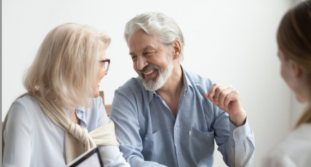 Two seniors smiling and talking in front of laptop computer